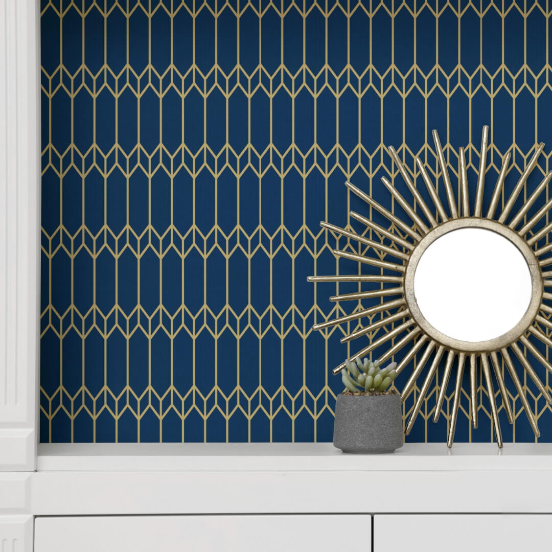 Navy-and-gold geometric peel and stick wallpaper accent wall in an apartment, styled with a gold sunburst mirror above a white console table.