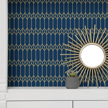 Navy-and-gold geometric peel and stick wallpaper accent wall in an apartment, styled with a gold sunburst mirror above a white console table.