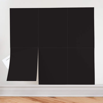 Six black peel and stick chalkboard sheets applied in a grid on a white wall, with one sheet peeled back at the lower left corner.