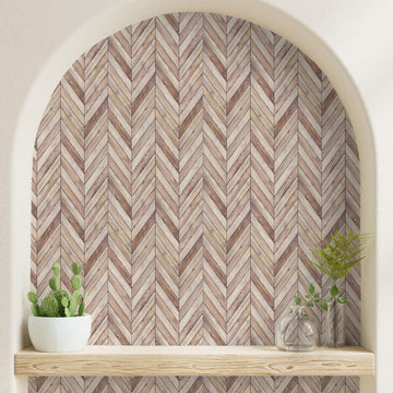 Arched wall niche lined with herringbone wood-pattern peel and stick sheets above a natural wood shelf holding plants and glass vases