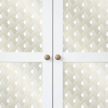 Close-up of white cabinet doors faced with gold geometric self-adhesive paper and finished with round brass knobs.