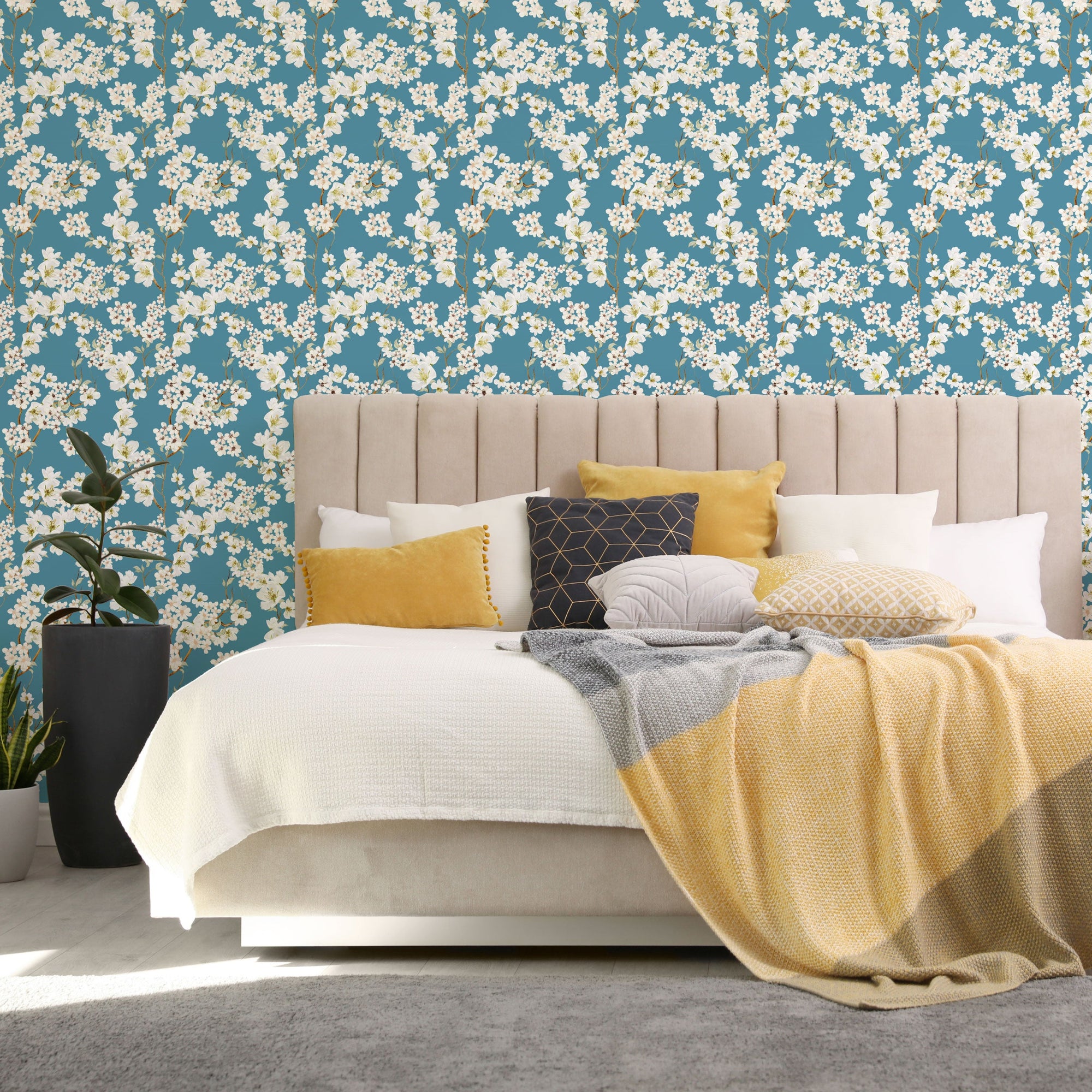 Magnolia Branches teal-blue blossom peel and stick wallpaper as a bedroom accent wall behind an upholstered headboard