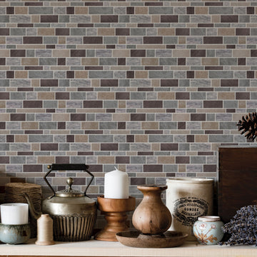 A wooden kitchen shelf holding a metal kettle, a stoneware crock, pillar candles and small jars, against a grey and tan mosaic tile wall.