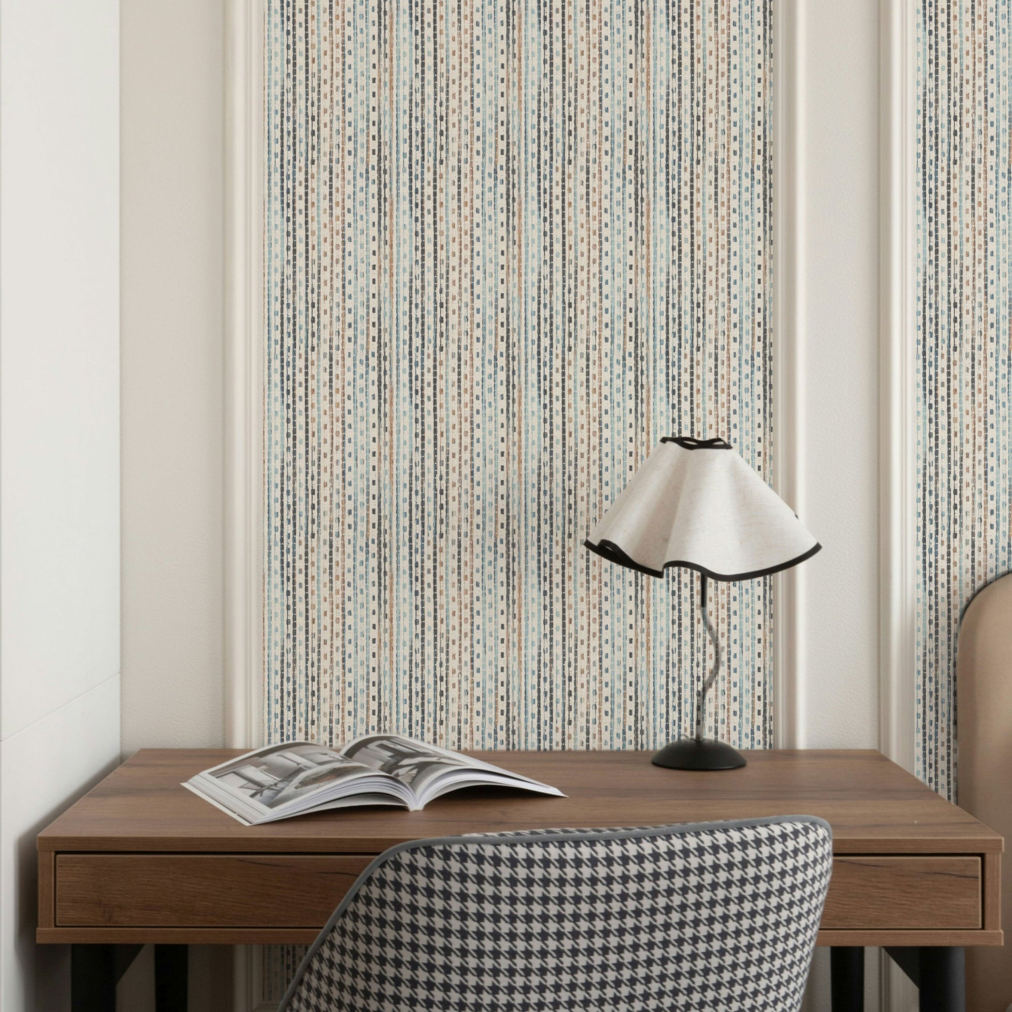 A wood desk and houndstooth chair below blue and tan striped wallpaper set inside crisp white wall trim.